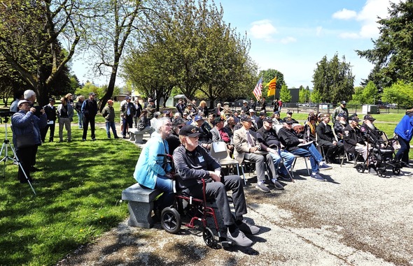Community members, including veterans, gather under sunny skies for the Black April commemoration ceremony.