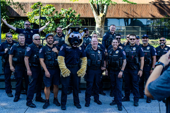 Group photo of Auburn police officers posing with a police dog mascot at a community event.