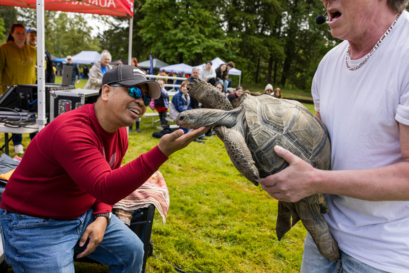 A man smiling and petting a large turtle