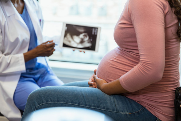 A stock image of a woman holding her pregnant belly 