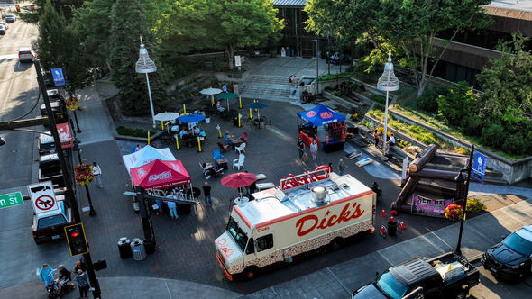 Aerial view of a summer evening event at Auburn City Hall with food trucks, tents, and games.