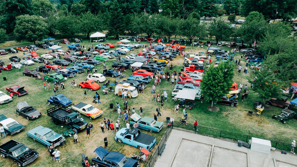 Aerial view of colorful classic cars and festivalgoers at an outdoor car show.
