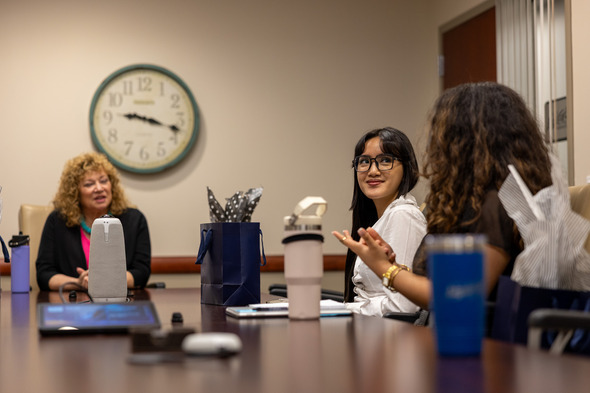 Group of young adults in a meeting room, one person speaking while others listen.
