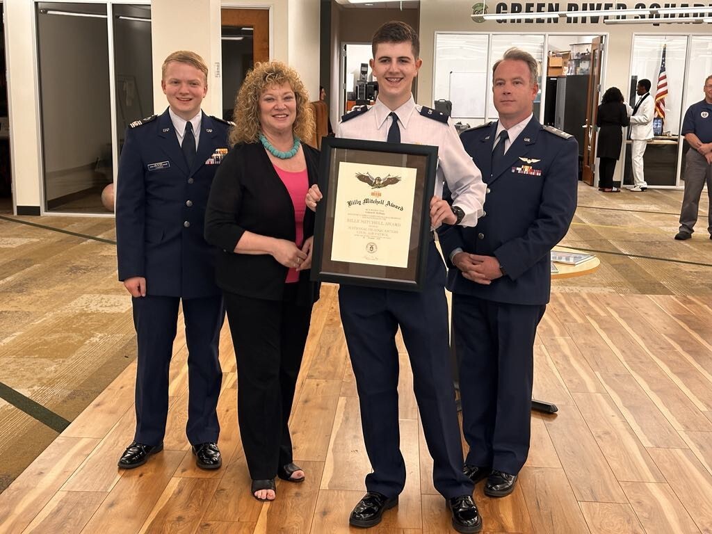 Cadet holds framed Billy Mitchell Award while posing with three people during a ceremony at Green River College.