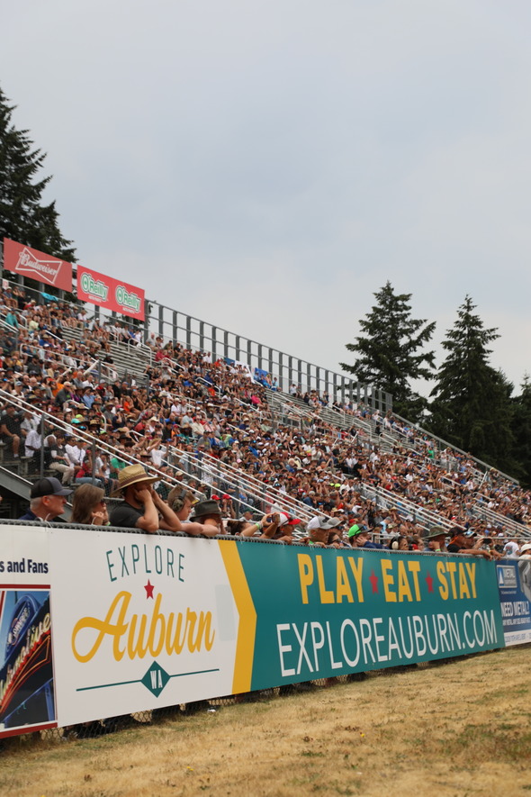 Large crowd in stadium seats behind a banner promoting Explore Auburn.