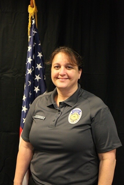 Auburn Police Department employee standing in front of a U.S. flag.