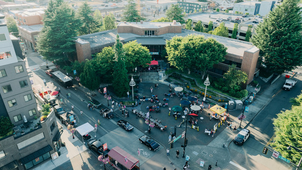 Aerial view of a lively event at Auburn City Hall Plaza with food trucks, booths, and people gathered in the plaza.