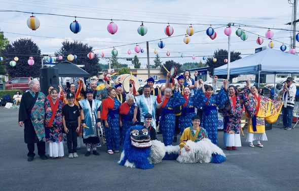 Performers in colorful Japanese attire pose under lanterns at Auburn’s Bon Odori Festival.