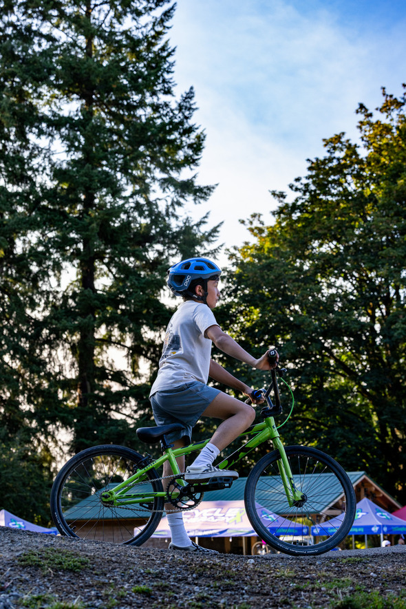 Child wearing a helmet riding a green bicycle in a park.