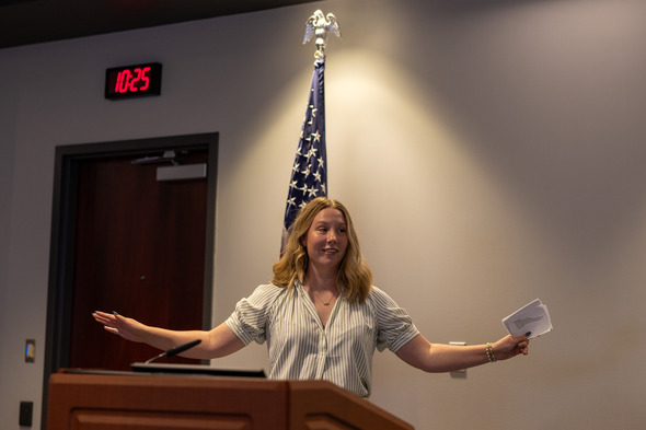 Woman speaking at a podium with an American flag behind her.