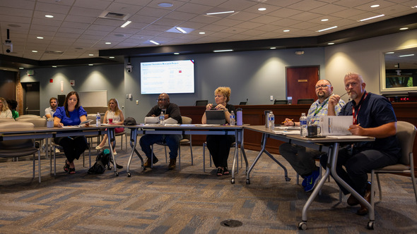 Group of people seated at tables in a conference room during a presentation.