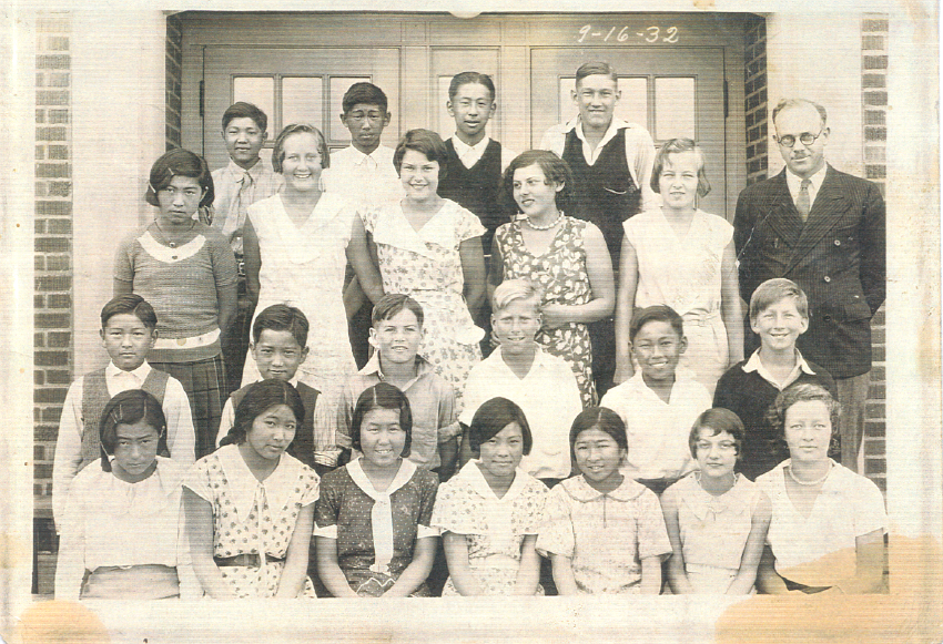 Black-and-white 1932 class photo of students and teachers posed in front of a brick school building.