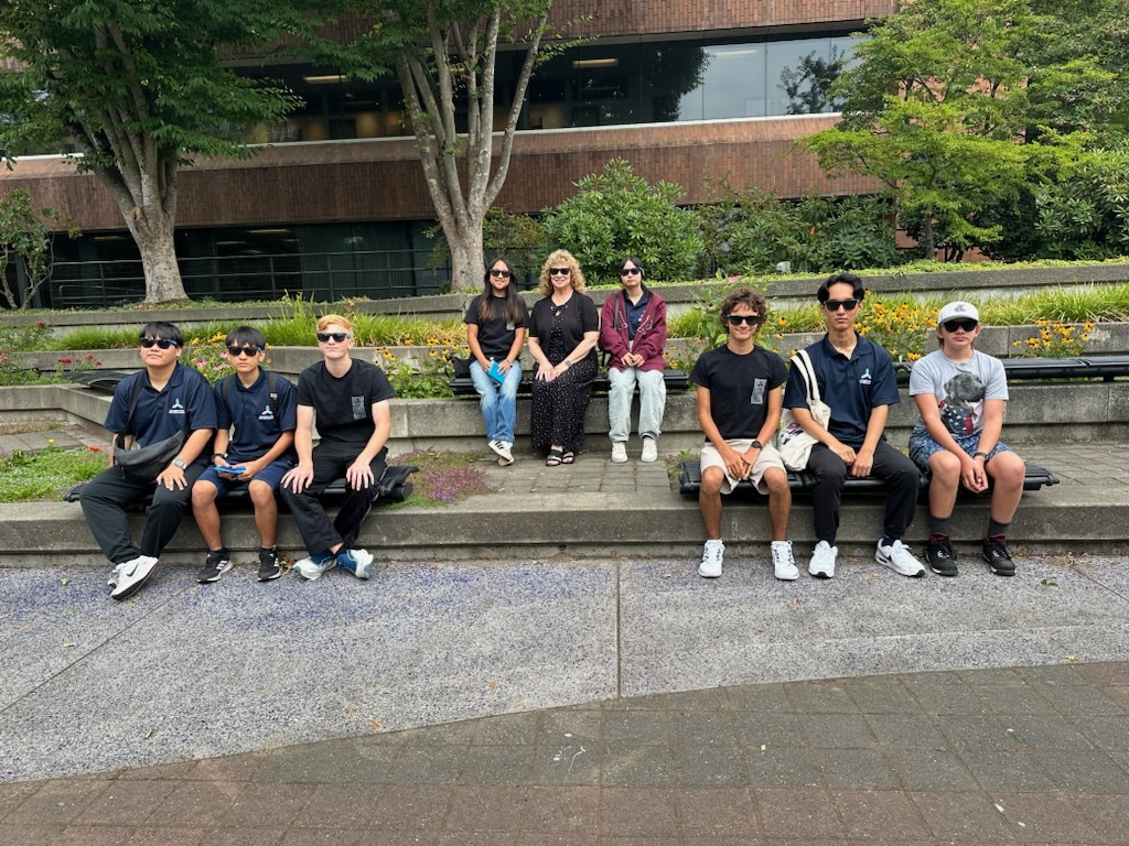 Group sitting on outdoor steps, smiling for a group photo.