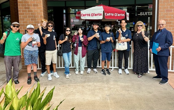 Group standing outside Caffé D’arte holding ice cream cones and cups, smiling at the camera.