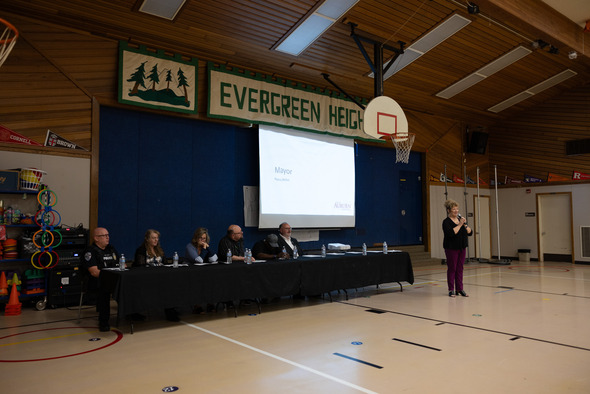 Panel discussion with Mayor Nancy Backus speaking in a school gym under an Evergreen Heights banner.