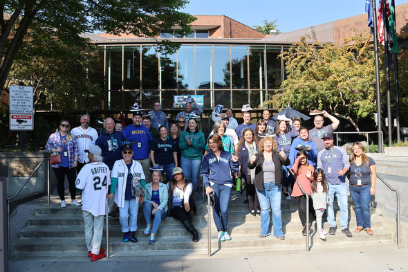 Large group of City of Auburn staff smiling on City Hall steps, many wearing Seattle Mariners gear.