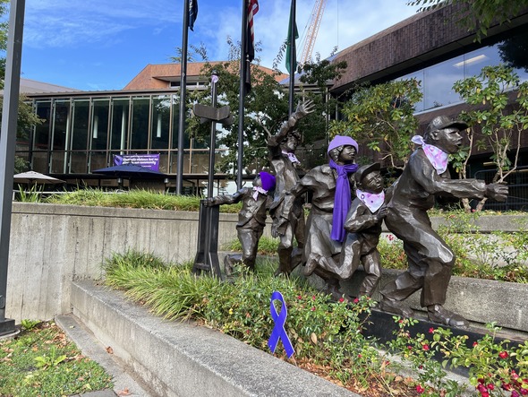 Bronze statues outside Auburn City Hall dressed in purple scarves for Domestic Violence Awareness Month.