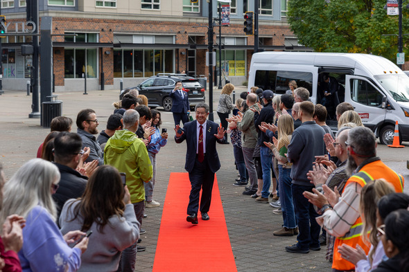 A man walks down a red carpet as a cheering crowd applauds in downtown Auburn.