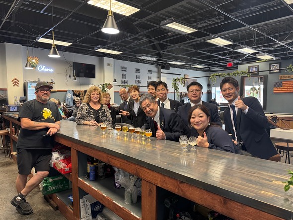 Mayor Backus and Tamba delegates enjoy a brewery visit with the owner behind the bar.