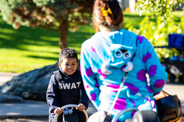 Young boy dressed as SWAT officer smiles while playing at the park during a fall event.