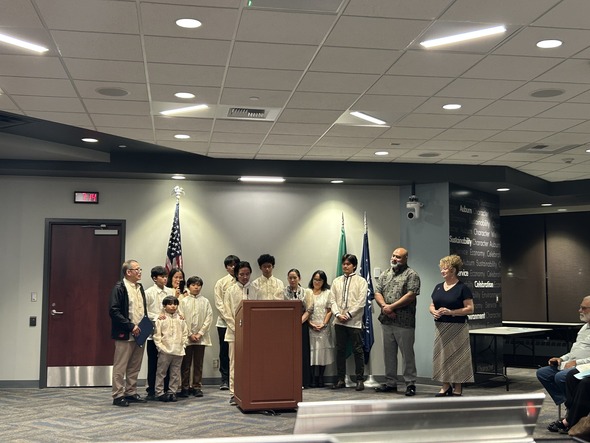 Group in traditional attire speaks at Auburn City Hall with Mayor Nancy Backus.