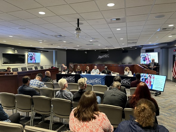Audience members listen as a panel of Auburn city staff and partners speak during a community meeting in City Hall Council Chambers.