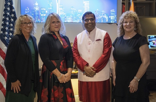 Guests in traditional attire talking and mingling inside a well-decorated living room.