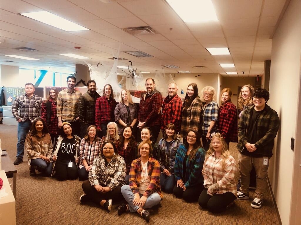City staff group photo in plaid flannel shirts for a themed day at the office.