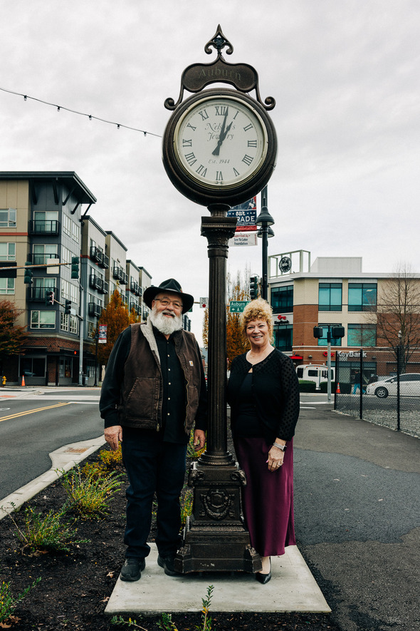 Two people stand beside Auburn’s historic street clock on a downtown sidewalk.