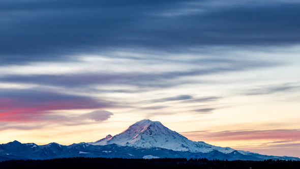 Snowy Mount Rainier at sunrise with pink and blue clouds stretching across the sky.