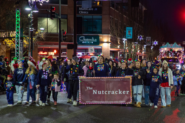 Children’s Dance Theater performers carry a Nutcracker banner while marching in a holiday parade.