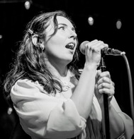 a woman with long hair holding a microphone in black and white