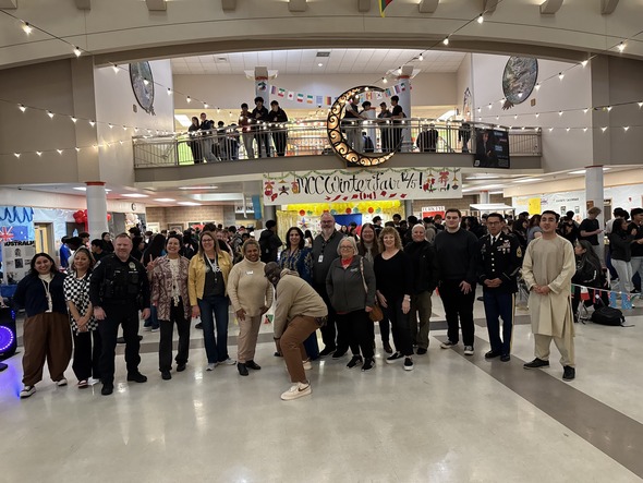 A group of community members and officials pose for a photo inside the busy MCCA Winter Fair event.