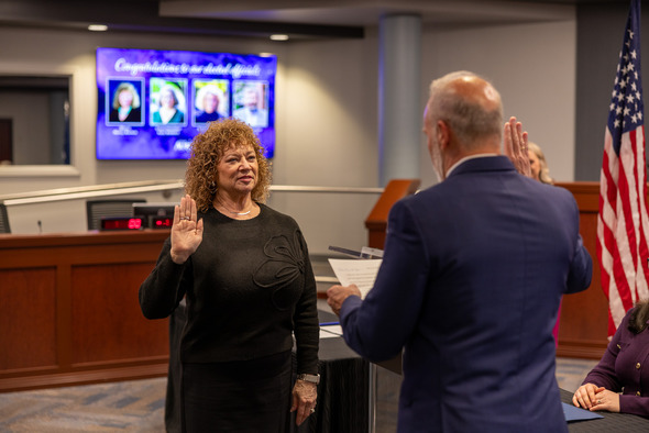 A woman raises her right hand while being sworn in during a City of Auburn council ceremony inside council chambers.