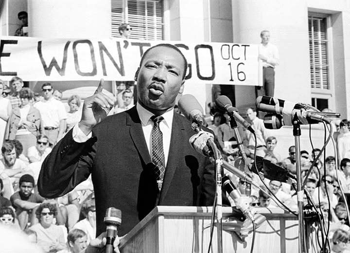 Black-and-white photo of Martin Luther King Jr. speaking at a podium during a civil rights rally.