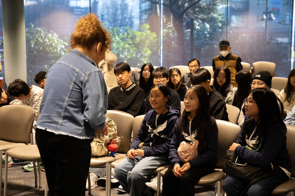 A woman talking to a roomful of students seated in chairs 