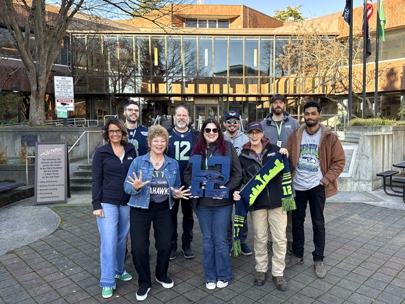 A group of people dressed in Seahawks gear standing in front of Auburn City Hall rallying 