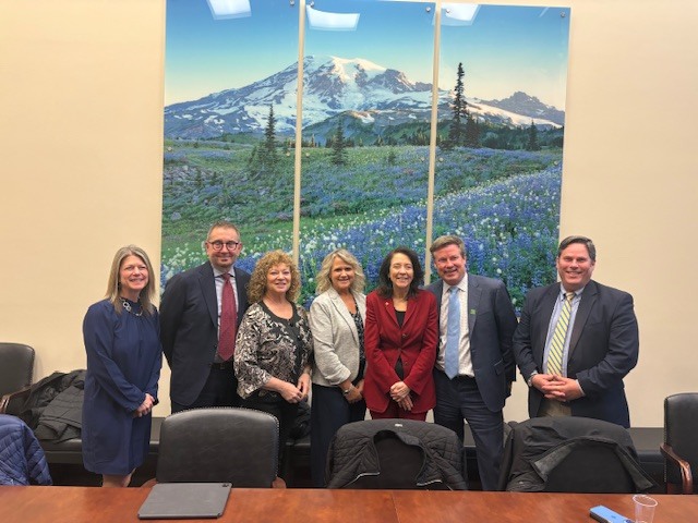 Group of Auburn officials standing in a conference room with Mount Rainier artwork behind them during meetings in Washington, D.C.