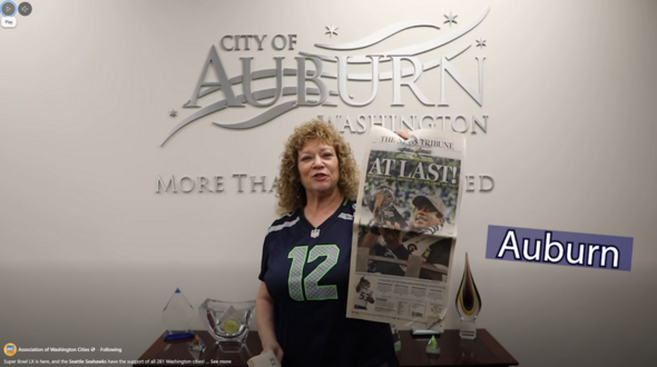 A screenshot of a Facebook video showing Mayor Nancy Backus holding up a newspaper. 