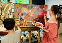 Two children painting on a canvas