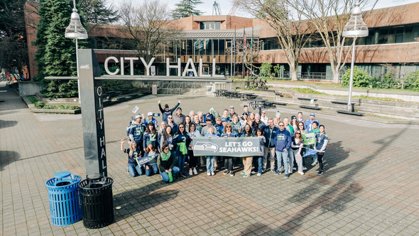 A large group of people in Seahawks gear in a plaza