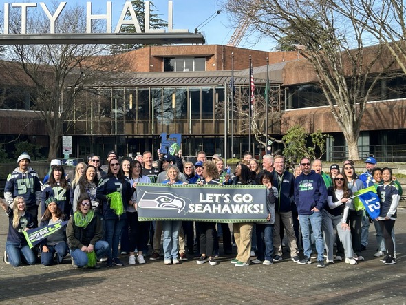 A large group of people in Seahawks gear in a plaza