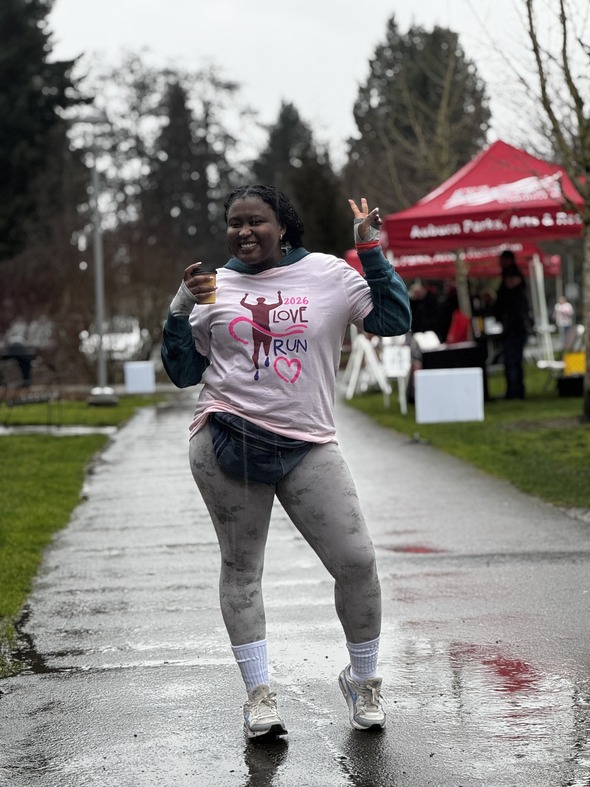 A woman standing doing a peace sign in the pouring rain 