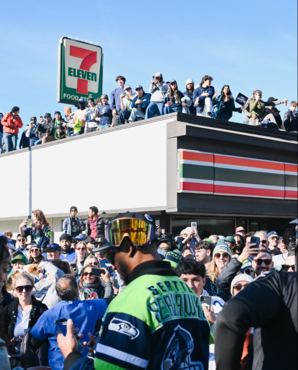 seahawks fans at a parade sitting and standing on a 7-Eleven convenience store 