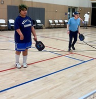 two people playing pickleball in a gym