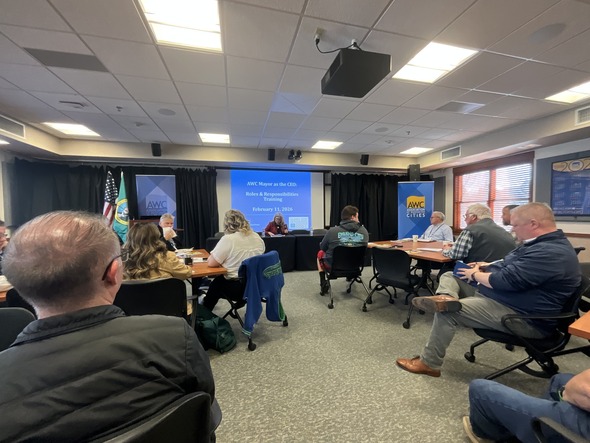 Attendees sit around tables facing a speaker during an AWC “Mayor as CEO” training session in a conference room.