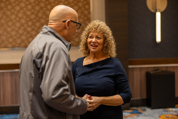 Mayor Nancy Backus speaks with attendee in ballroom before State of the City event.