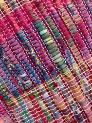 Close-up of colorful woven textile with red, blue, and multicolored fabric strips stitched together.