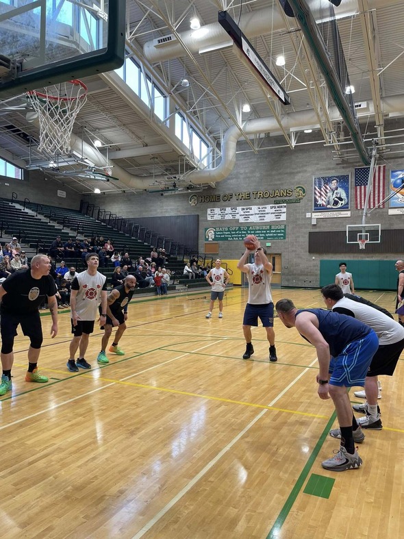 Player shoots free throw during community basketball game in Auburn High gym with spectators watching.