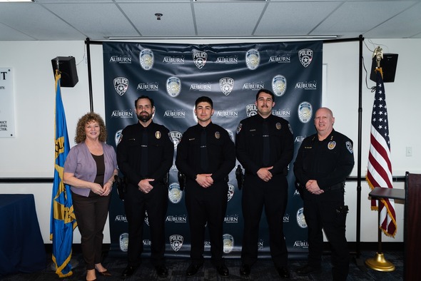 Mayor Backus stands with four Auburn police officers during a formal ceremony.